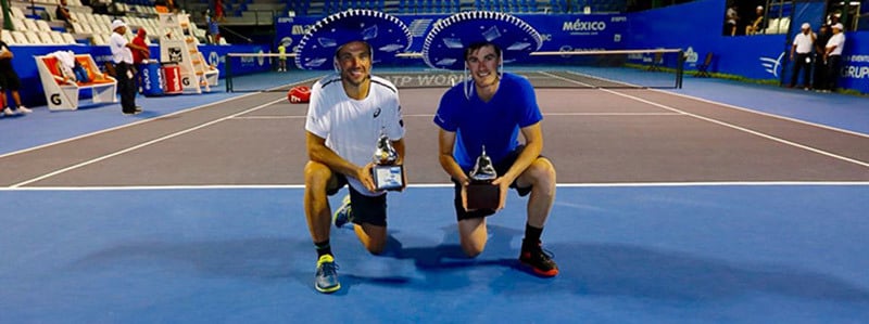Jami Murray and Bruno Soares kneeling with their awards in hand on a tennis court