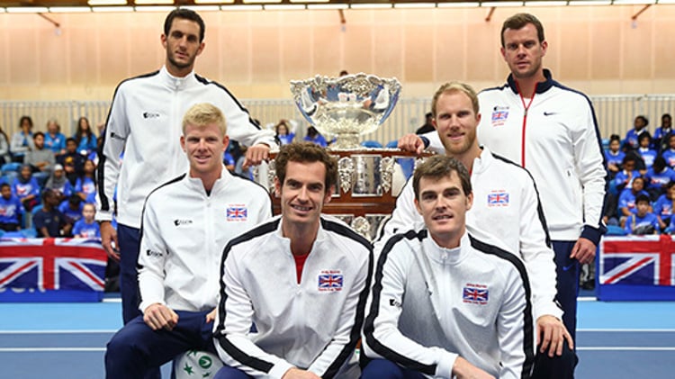 6 members of davis cup team standing and sitting around big silver trophy with GB flags at the bag