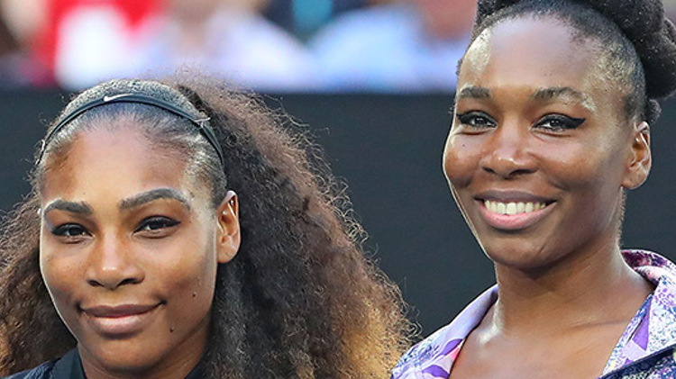 Serena and Venus Williams smiling next to each other on a tennis court