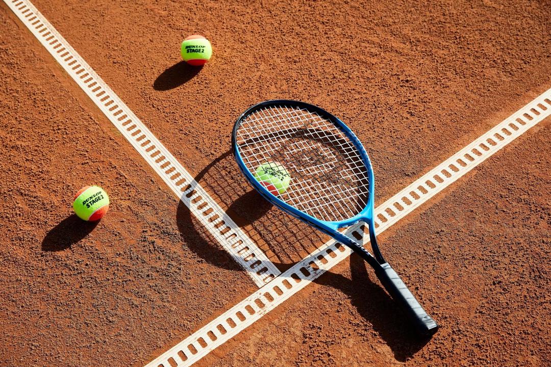 Close up of tennis racket and balls on clay court