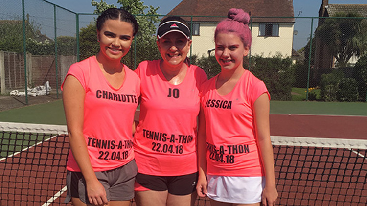 Jo Stehle standing on court with her two daughters wearing pink tennis-a-thon t-shirts
