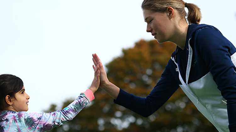 kid hi-fiving with adult coach