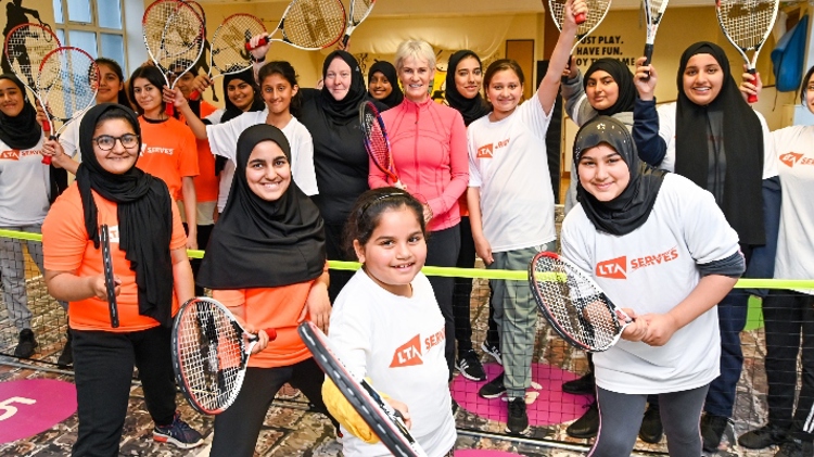 nalette tucker and judy murray standing between a group of kids wearing lta serves tops all holding rackets up 