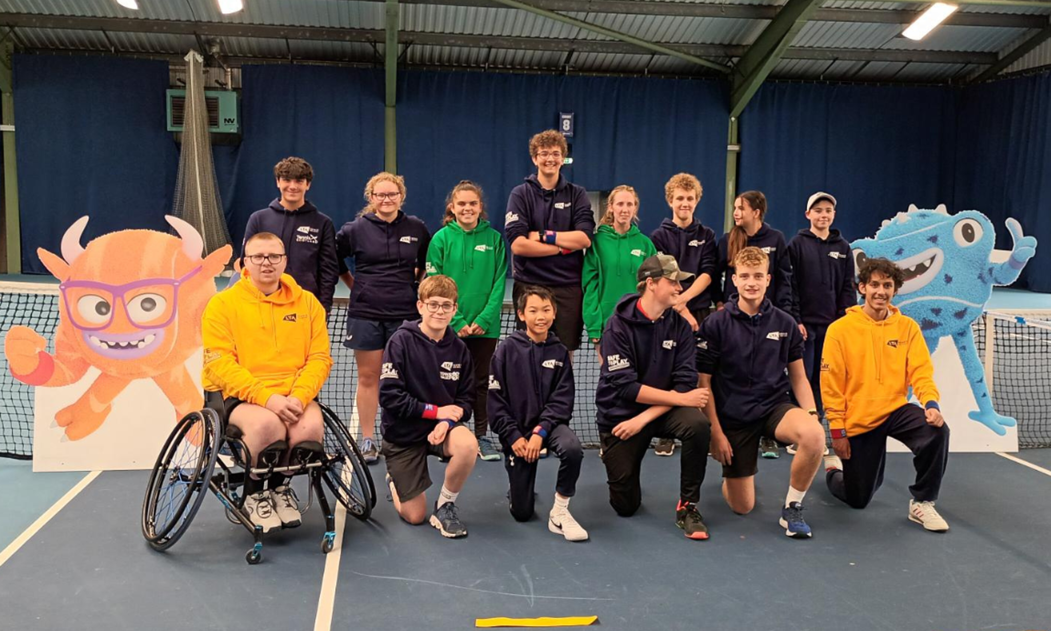 A group of Young Person's Welfare Ambassadors smiling and posing for a photo with some Tennisables characters.
